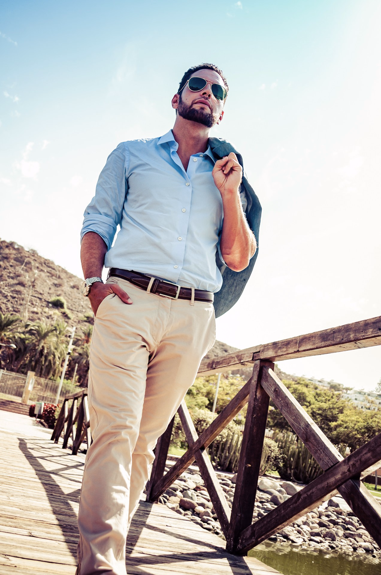 A wooden boardwalk in the Maspalomas South Park, Gran Canaria. Alexander, companion for women, jacket over the shoulder and sunglasses.