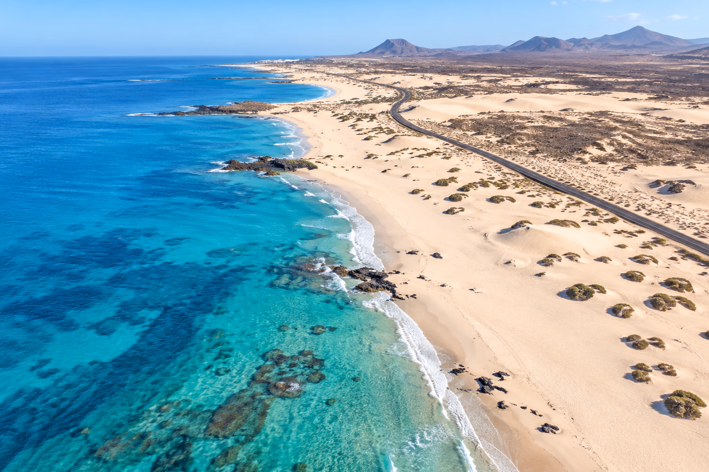 Die weißen Dünen von Corralejo, die zu einem türkisblauen Meer abfallen, von oben gesehen