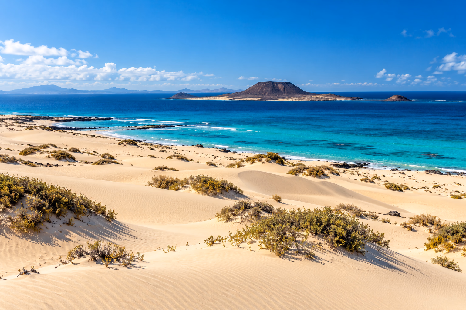 Die weißen Dünen von Corralejo über dem türkisblauen Meer, mit der Isla de Lobos am Horizont