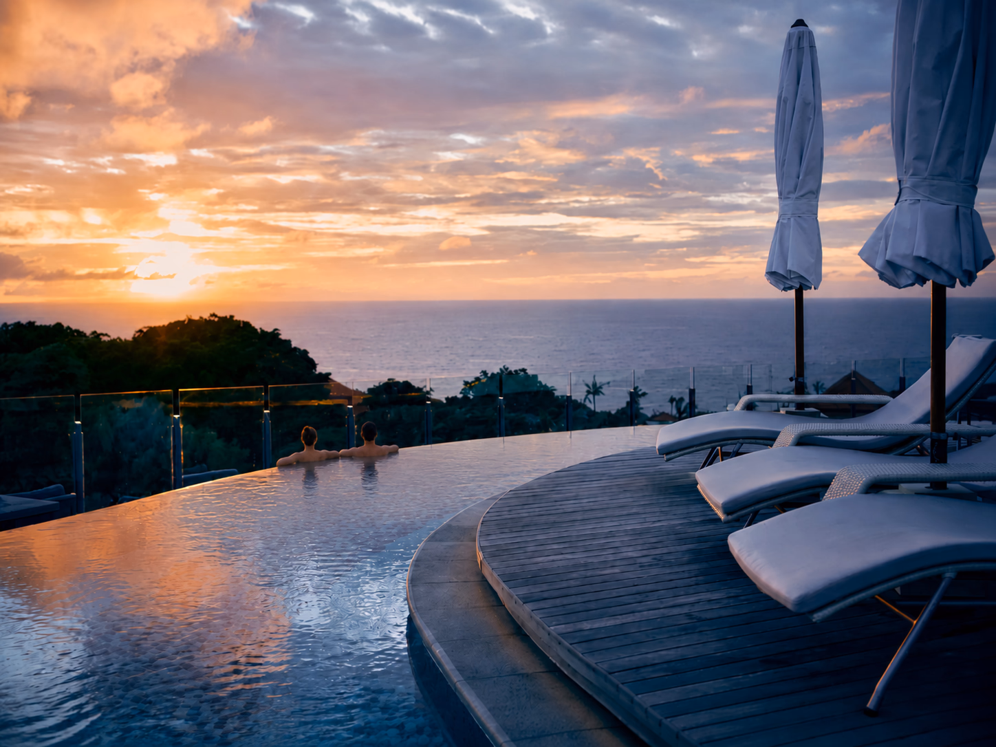 Infinity pool overlooking the sea at sunset, loungers and parasols. The ease of a stay with Alexander, escort for women.